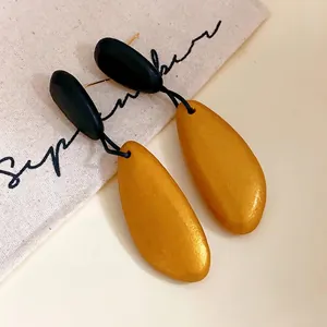 Pendientes colgantes de madera vintage en oro y negro con elegante acabado mate.