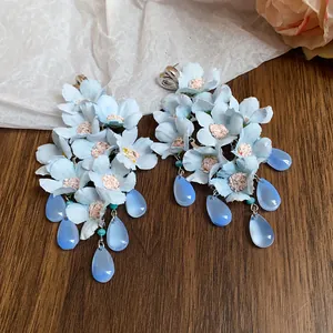 Primo piano di orecchini a fiori azzurri con nappe e gocce di vetro blu lucido