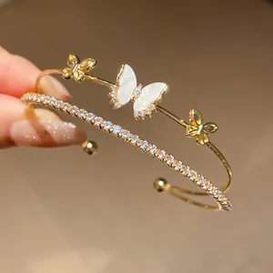 Primer plano detallado de brazalete dorado de doble capa con mariposa de circón y pavé.