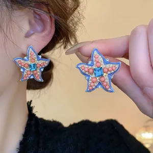 Detailed view showing starfish earrings with coral beads and blue crystal center