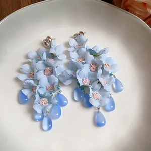 Vista dettagliata di eleganti orecchini a fiore in tessuto azzurro con gocce di vetro