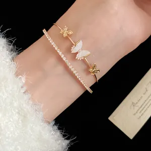 Primer plano elegante de pulsera dorada de doble capa con mariposa de nácar y circonitas