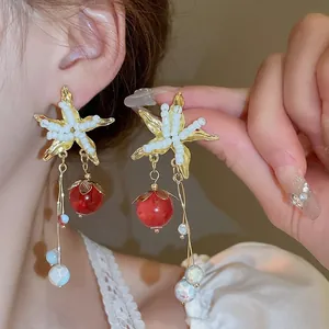 Detailed view of elegant starfish drop earrings with white seed beads and red bead accents