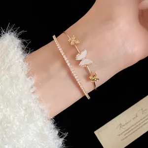 Primer plano de una elegante pulsera dorada de doble capa con circonitas y dijes mariposa