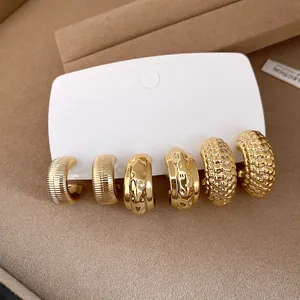 Juego de tres pares de pendientes de aro dorados en forma de C con varias texturas de diseño.
