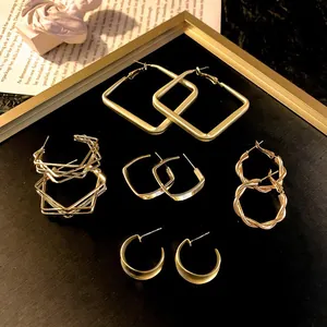 Elegant assorted gold geometric hoop earrings set displayed on dark background with frame