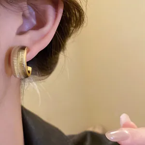 Detalle de primer plano de elegantes pendientes dorados en forma de C con textura