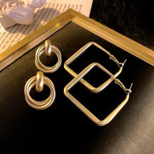 Macro view of matte gold geometric hoop earrings including round and square shapes