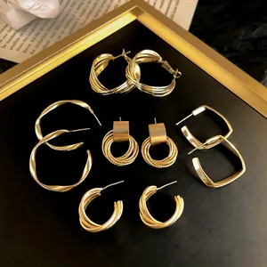 Macro detail of various gold geometric hoop earrings with matte and polished finishes.