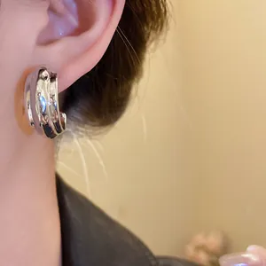 Primer plano de la textura martillada de los pendientes de aro plateados en forma de C.