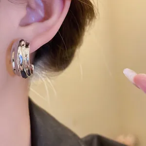 Primer plano de un pendiente de aro plateado con textura en forma de C en la oreja