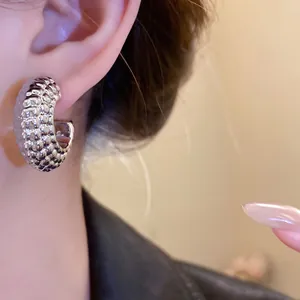 Primer plano de pendientes de aro plateados en forma de C con textura en la oreja