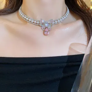 Elegant sparkling bow choker necklace with pearls and pink pear-shaped zircon on model