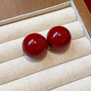 Dettaglio macro di eleganti orecchini a bottone rossi in un portagioie in tessuto