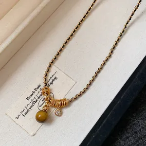 Vue détaillée d'un collier en œil de tigre plaqué or avec zircon et accents de style Maillard