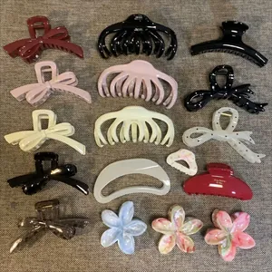Collection of minimalist hair claw clips in various shapes and colors on grey background