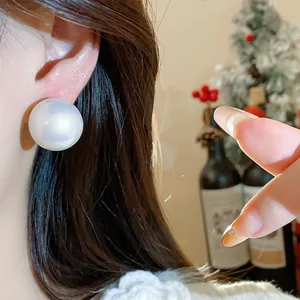 Primo piano di un elegante orecchino a bottone con perla bianca oversize in stile francese chic