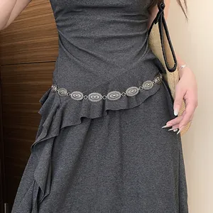 Close-up view of a vintage silver oval waist chain on a grey dress for fashion accessory