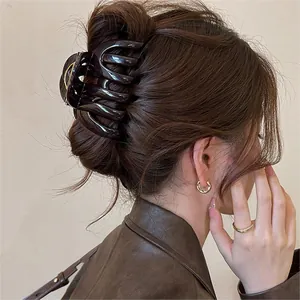 Elegant dark brown glossy shark hair claw clip shown in use on a model's hair bun