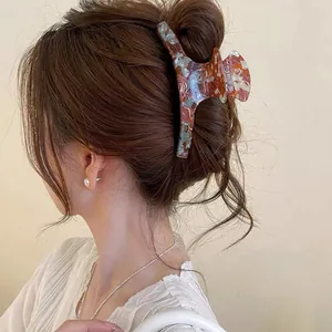 Detailed side view of an elegant marble patterned hair claw clip in brown hair