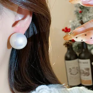 Dettaglio di un elegante orecchino a bottone con perla bianca, stile francese minimal