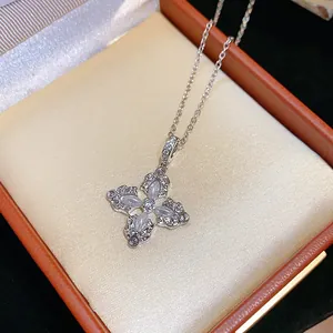 Dettaglio di una collana a croce con fiori in argento e zirconi in una scatola arancione.