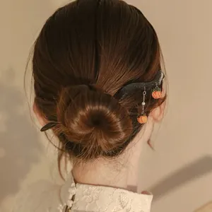 Detailansicht eines hölzernen Haarstabs mit Anhängern in einem eleganten Dutt