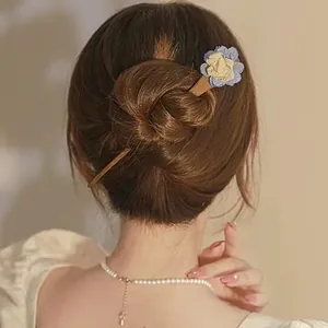 Detailansicht einer Vintage-Holzhaarnadel mit zartem Blumendetail in einem eleganten Haarknoten