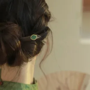Nahaufnahme einer vintage Holzhaarspange mit grünem Jade-Inlay in einem traditionellen Dutt