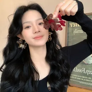 Asian model wearing large leopard and burgundy fabric flower earrings in a lifestyle setting