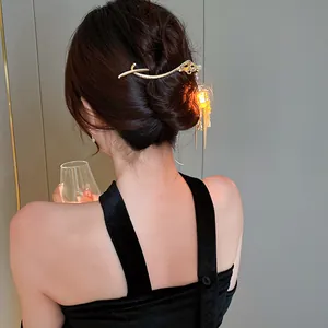 Close-up detail of a glowing lantern hair stick with pearl tassels on a styled hair bun