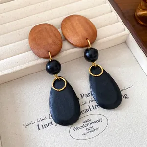 Close-up of vintage wooden teardrop earrings with black beads in a jewelry box