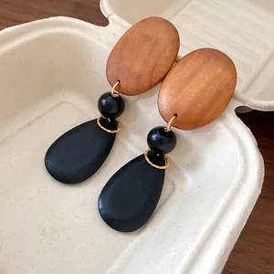 Macro detail view of vintage wood bead teardrop earrings on a neutral textured tray