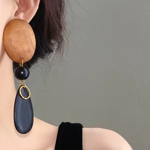 Close-up of vintage wooden drop earrings with oval and teardrop shapes on model