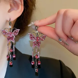 Close-up of pink crystal butterfly drop earrings with sparkling tassels