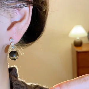 Eleganti orecchini a pendolo con zirconi e una pietra naturale a sfera di occhio di tigre oro.