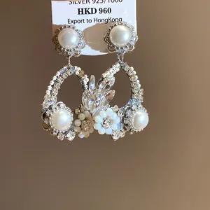 Primo piano dettagliato di eleganti orecchini floreali con perle e lucenti cristalli.
