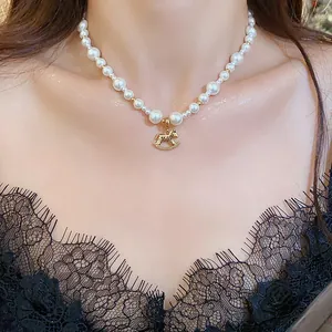 Elegant close-up view of gold-plated rocking horse pendant on a white pearl necklace