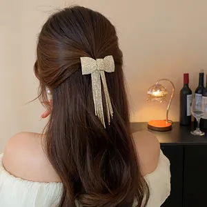 Detail of elegant rhinestone bow hair clip with long tassels on dark hair.