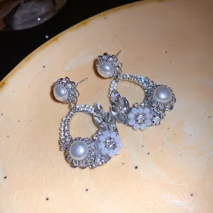 Dettaglio di eleganti orecchini in stile francese con perle e cristalli lucenti