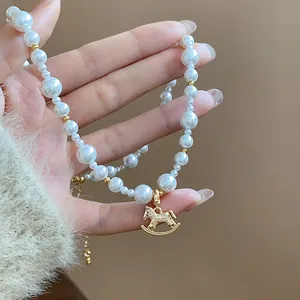 Detail of a French style pearl necklace with an 18k gold plated rocking horse charm