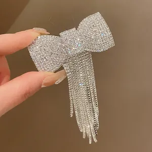 Close-up detail of a sparkling silver rhinestone bow hair clip with elegant tassel fringe