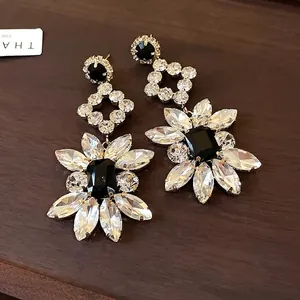Elegant silver needle drop earrings featuring black crystal centers and floral rhinestone petals