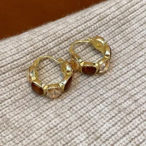 Detaillierte Nahaufnahme von goldenen Vintage-U-Ohrringen mit braunem Harz und Strass