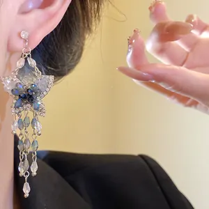 Primo piano dettagliato di eleganti orecchini a farfalla con cristalli blu su modella