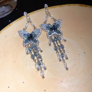 Eleganti orecchini a farfalla con nappe, cristalli blu e raffinati dettagli in strass.