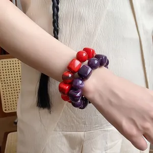 Detailed view of red and purple irregular geometric acrylic beaded bracelets on wrist