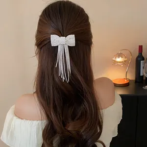 Elegant sparkling bow hair clip with tassel fringe shown on wavy brown hair