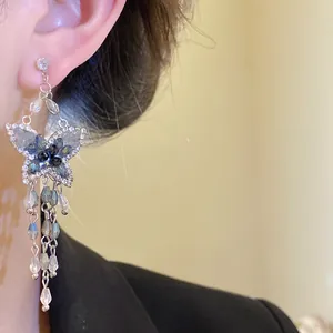 Primo piano di eleganti orecchini a farfalla con nappe, cristalli blu e perni in argento