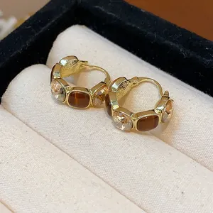 Detaillierte Nahaufnahme von goldenen Vintage-Creolen mit braunem Harz und klaren Kristallen